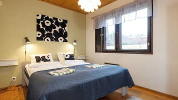Un dormitorio con cama, lámpara de pared, ventana con cortinas e iluminación en el techo.
