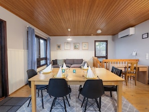 A dining area with a wooden table, black chairs, and a wooden bench. There are framed pictures on the wall and a window with curtains. - Villa-lyydia by Interhome (Hämeenlinna)