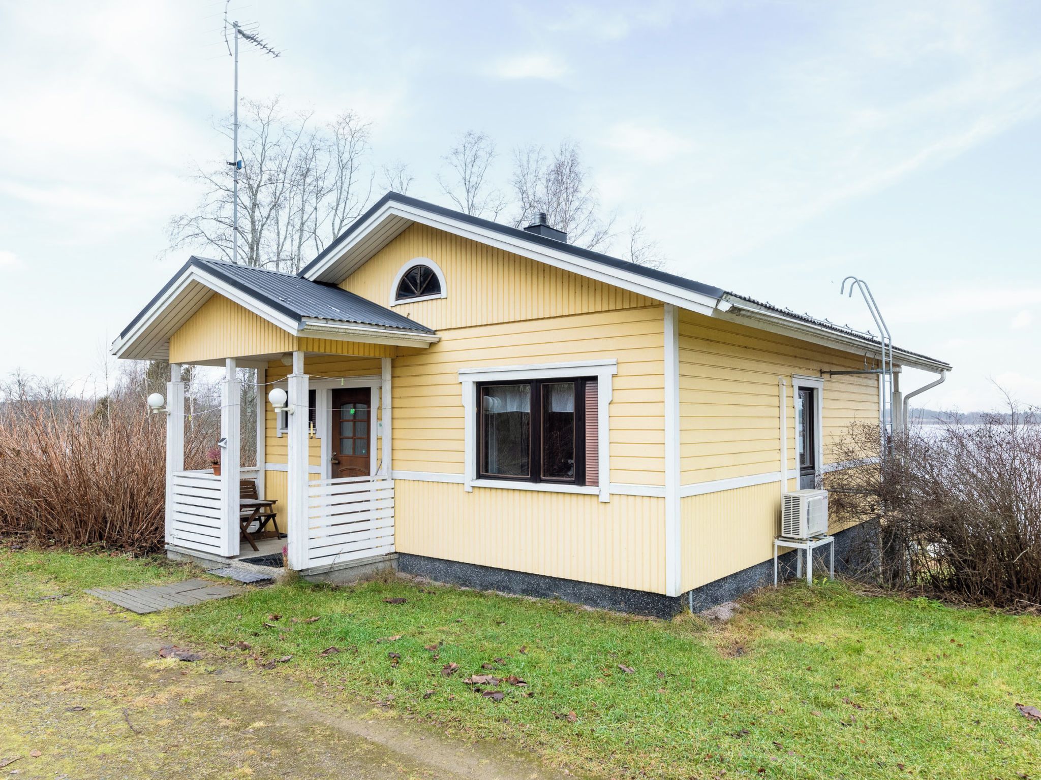 A yellow single-story house with a porch, a chimney, and a satellite dish.