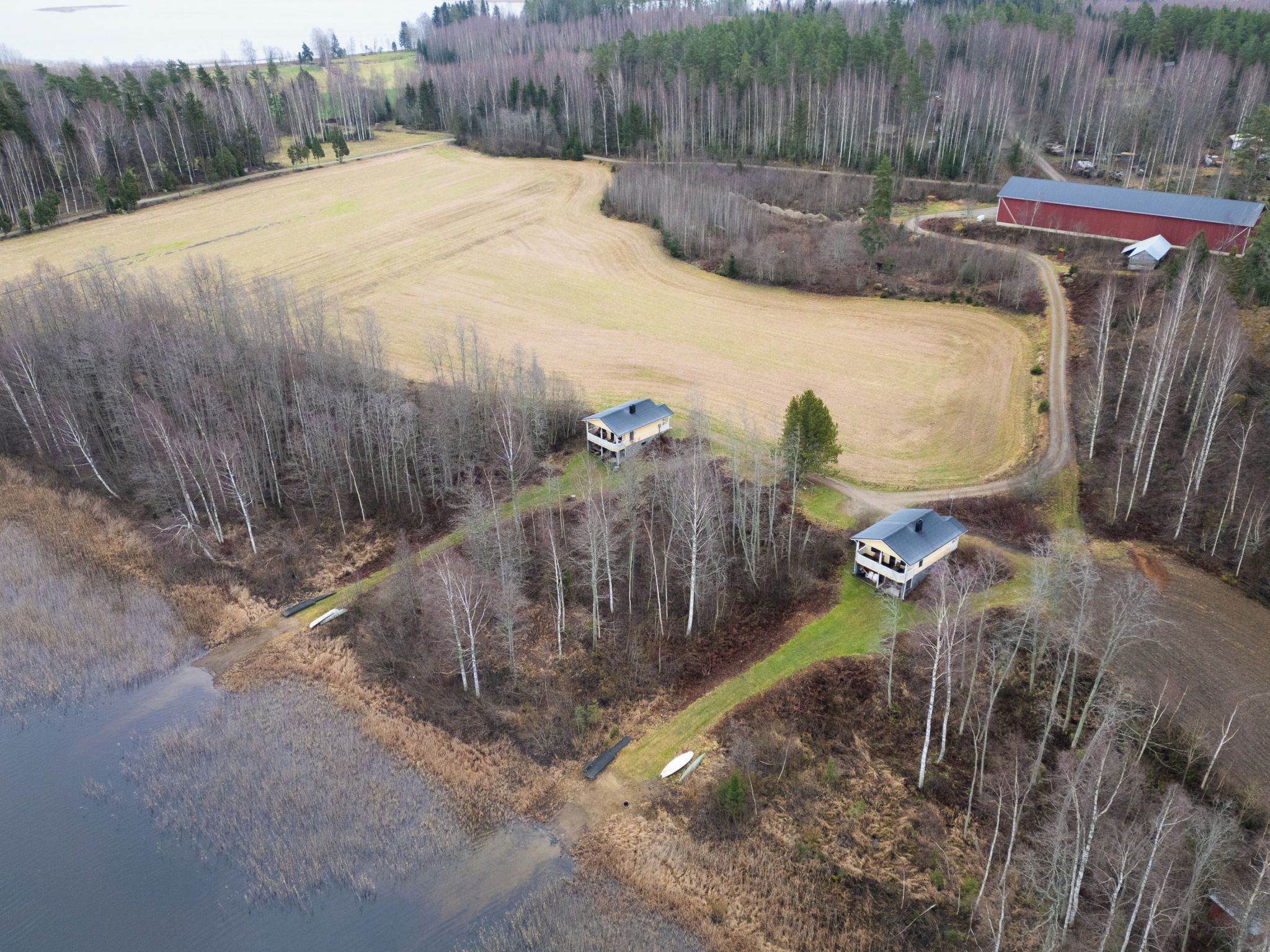 An aerial view of a rural property with two houses, a barn, and a large open field.