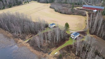 An aerial view of a rural property with two houses, a barn, and a large open field.