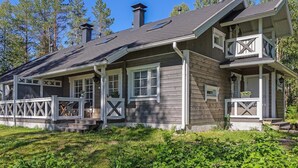 A two-story wooden house with a balcony, a chimney, and a porch with a railing. - Aallotar havina by Interhome (Paltamo)