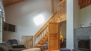 A cozy living room with a sofa, a fireplace, and a staircase leading to an upper level. - Aallotar havina by Interhome (Paltamo)