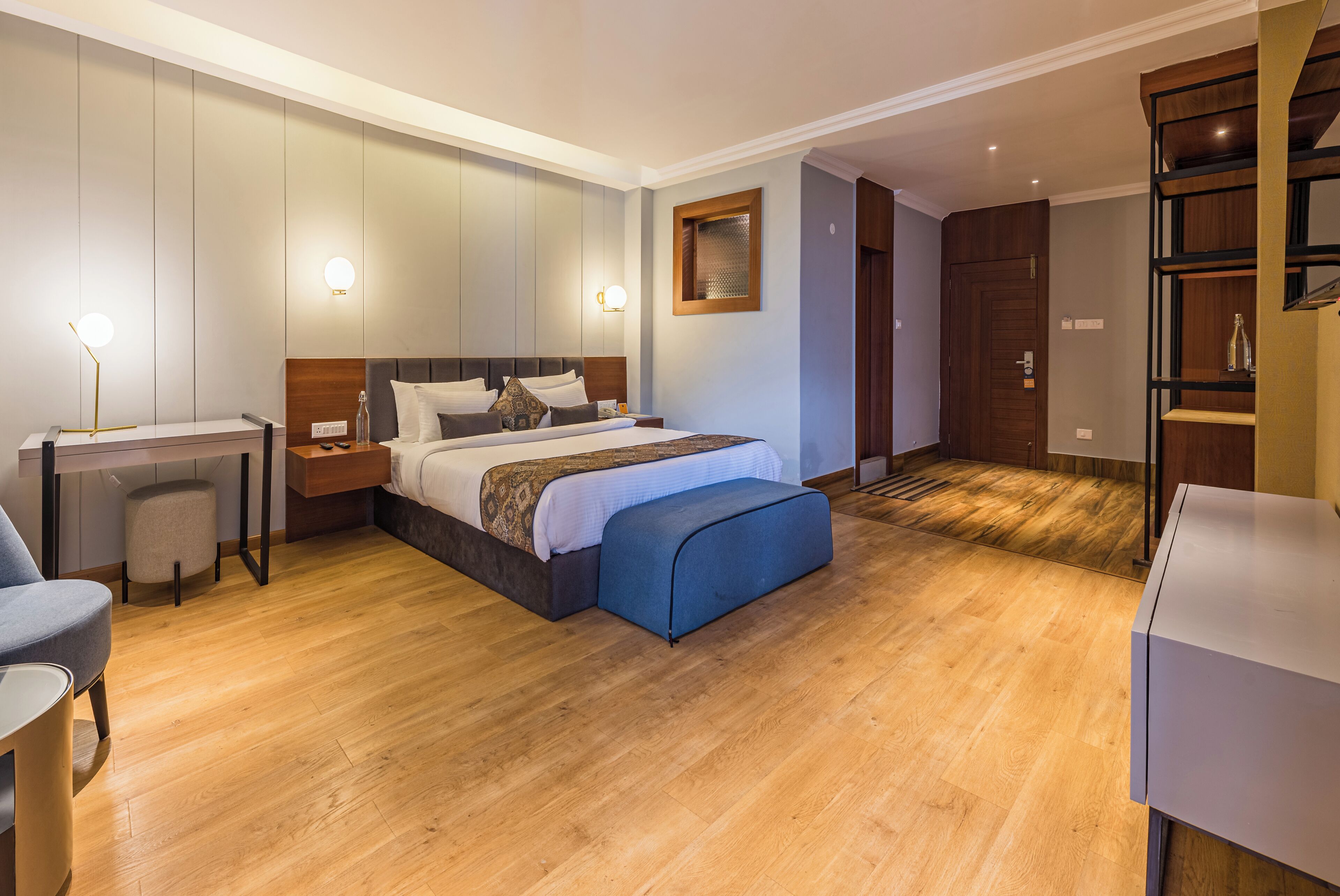 Una habitación de hotel moderna con una cama grande, mesitas de noche, un escritorio y un armario.