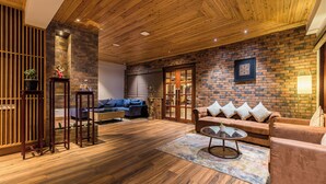 Un salon chaleureux avec un plancher en bois, un mur décoratif en briques, un ensemble de canapés et une table basse.