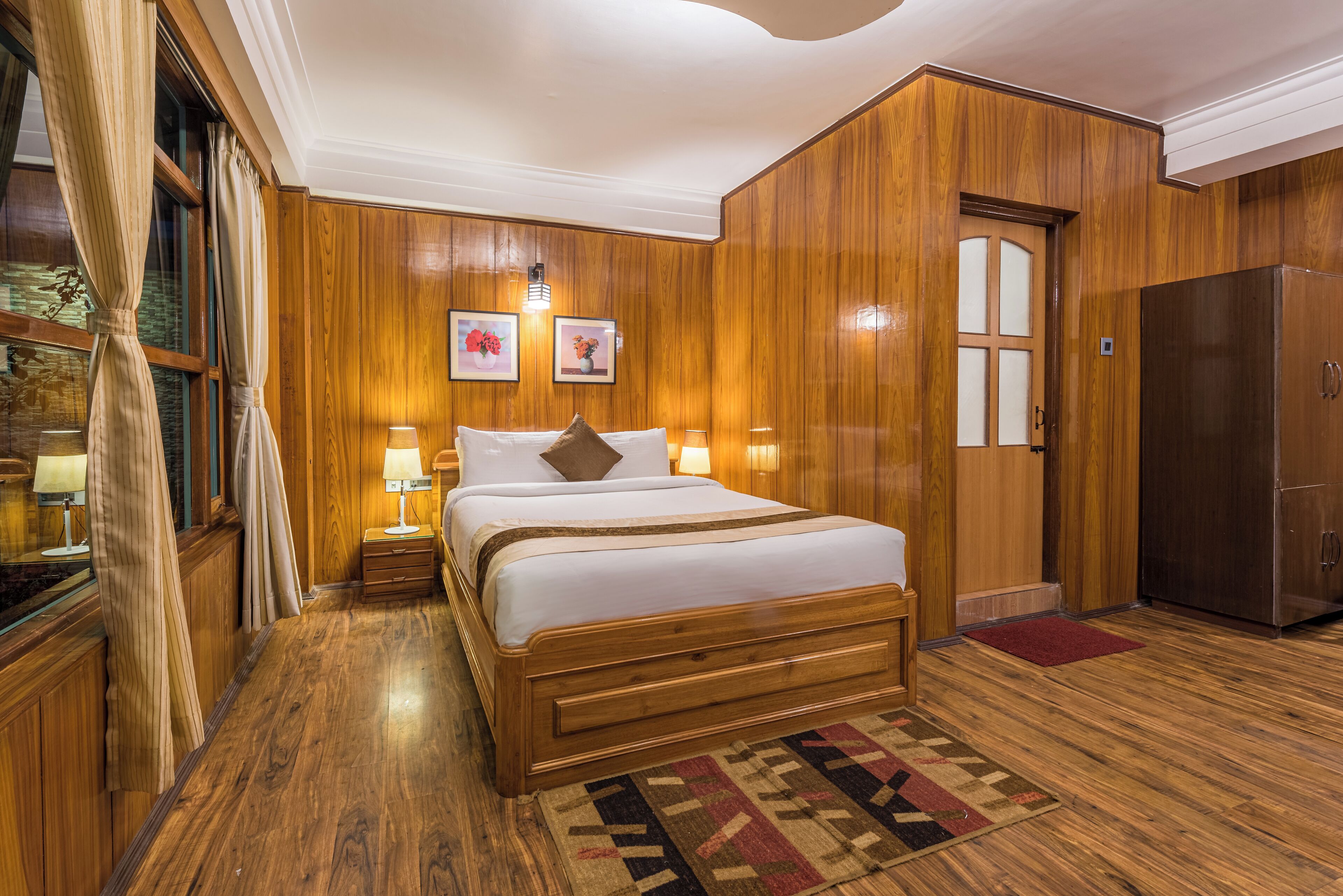 Ein Schlafzimmer mit Holzvertäfelung, einem großen Bett, Nachttischlampen und einem Kühlschrank.