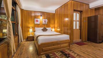 Un dormitorio con paneles de madera, una cama grande, lámparas de noche y un refrigerador.