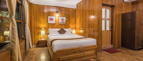 Ein Schlafzimmer mit Holzvertäfelung, einem großen Bett, Nachttischlampen und einem Kühlschrank.