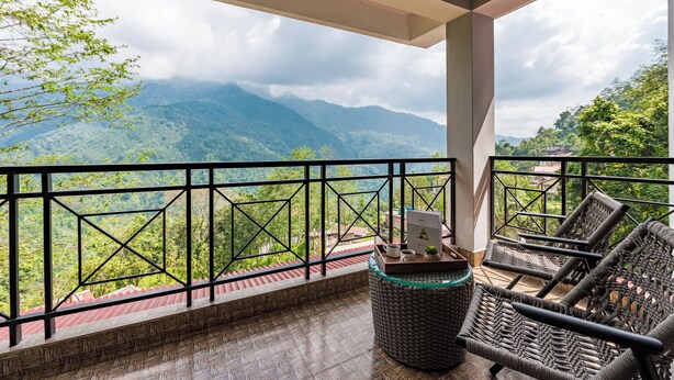 Un balcon avec des fauteuils en osier, une petite table et une vue sur les montagnes.