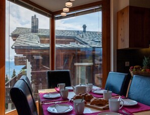 Enjoy breakfast in this cozy dining area with a view of a traditional chalet.