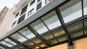 A modern hotel entrance with a glass facade, a staircase leading to the entrance, and a metal railing. - Privato Makati (Makati)
