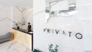 A reception desk with a marble wall and the word "PRIVATO" in letters. - Privato Makati (Makati)