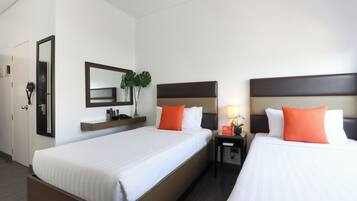 Een hotelkamer met twee bedden, een nachtkastje, een spiegel en een tafeltje met een lamp.