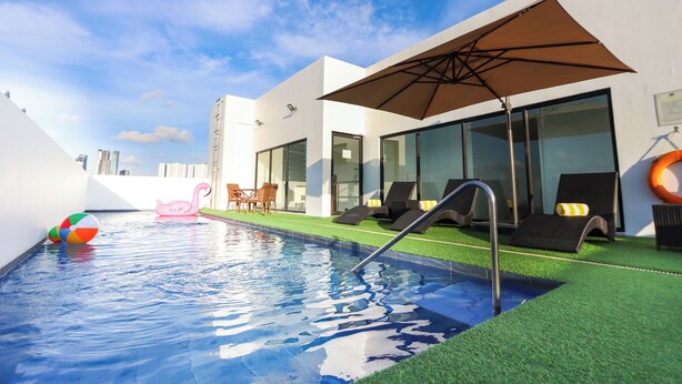 A swimming pool with a diving board, lounge chairs, and a beach ball. - Privato Makati (Makati)