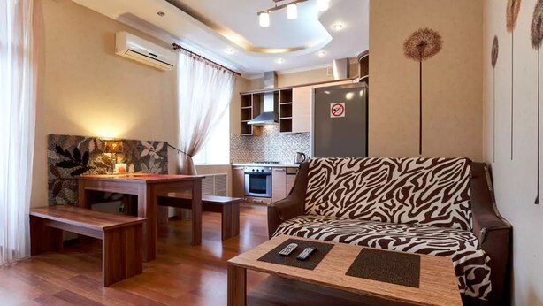 Een moderne woonkamer met een sofa met een zebraprint, een houten salontafel en een kleine eethoek.