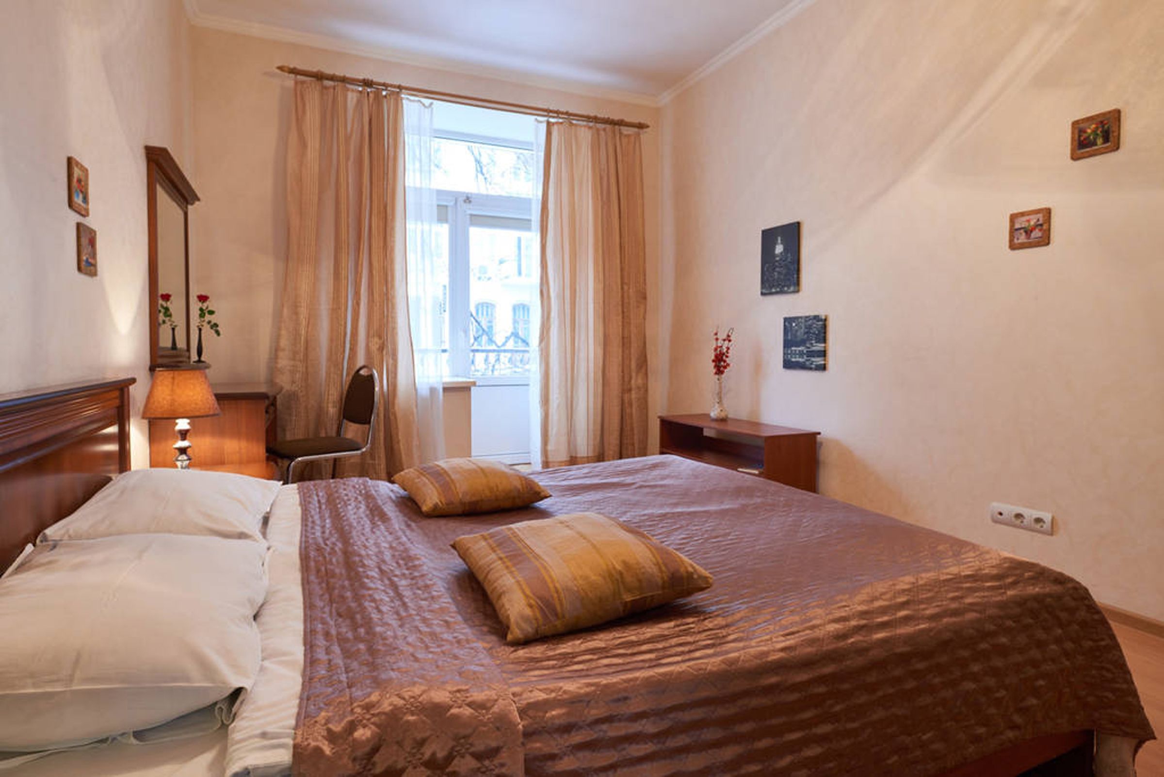 A hotel room with a bed, a chair, a desk, and a window with curtains.