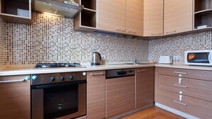 Een moderne keuken met houten kastjes, een roestvrijstalen fornuis en een betegelde achterwand.