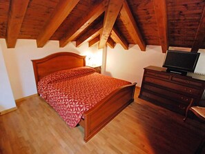 A bedroom with a wooden bed, a dresser, and a television.