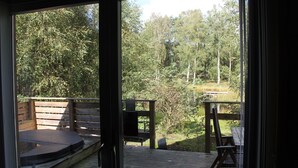 A wooden deck with a hot tub, a bench, and a table, overlooking a forested area. - Äventyrscampen in Sövde (Sjobo)