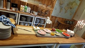 A buffet setup with various food items and condiments on a wooden table, surrounded by kitchenware and utensils. - Äventyrscampen in Sövde (Sjobo)