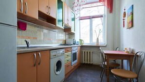 Une cuisine de taille réduite, équipée des appareils électroménagers de base, avec une table et des chaises pour prendre les repas.