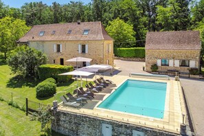 Ein Gebäude aus Stein mit Swimmingpool, Sitzgelegenheiten im Freien und einem Garten.