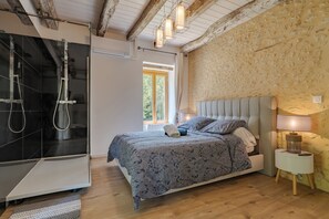 Ein Schlafzimmer mit Bett, Nachttisch, Lampe und einer Duschkabine.