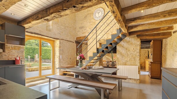 Eine moderne Küche mit einer Steinwand, einer Holztreppe und einem großen Fenster.
