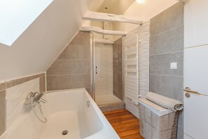 Une salle de bain moderne avec une baignoire, une douche et un plancher en bois.