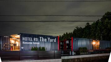A modern hotel with a vertical striped facade and a sign reading "HOTEL RS The Yard Kanuma Sakee".