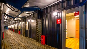 A corridor with metal doors, each marked with a number and a red sign indicating a "Smoking Machine." - HOTEL R9 The Yard Kanumasakae (Kanuma)