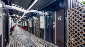 A corridor with numbered doors, a wooden floor, and overhead lighting. - HOTEL R9 The Yard Kanumasakae (Kanuma)