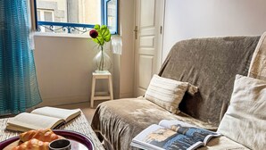 A cozy room with a sofa, a small table with a tray of croissants and cups, a book, and a vase with a flower. - Le Vieux Port by Interhome (Cancale)