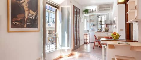 A spacious living area with a large window, a kitchen with a dining area, and a staircase leading to another level.