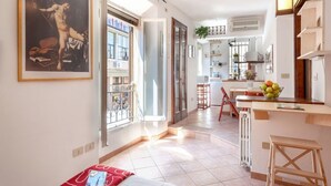 A spacious living area with a large window, a kitchen with a dining area, and a staircase leading to another level.