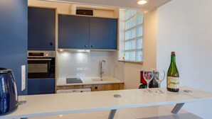 Una cocina moderna con armarios azules, una encimera blanca y una botella de vino.