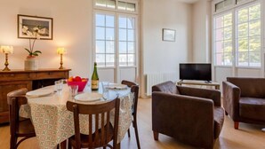 Un comedor con una mesa dispuesta para cuatro personas, un televisor y dos sofás.