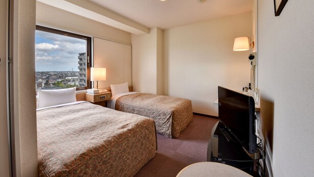A hotel room with two beds, a TV, a lamp, and a window with a city view. - Ichihara Inn Social Goi (Ichihara)