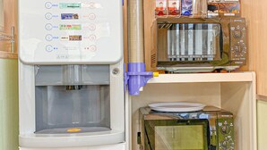 A kitchenette with a water dispenser, a microwave, and a shelf with packaged food items. - Ichihara Inn Social Goi (Ichihara)