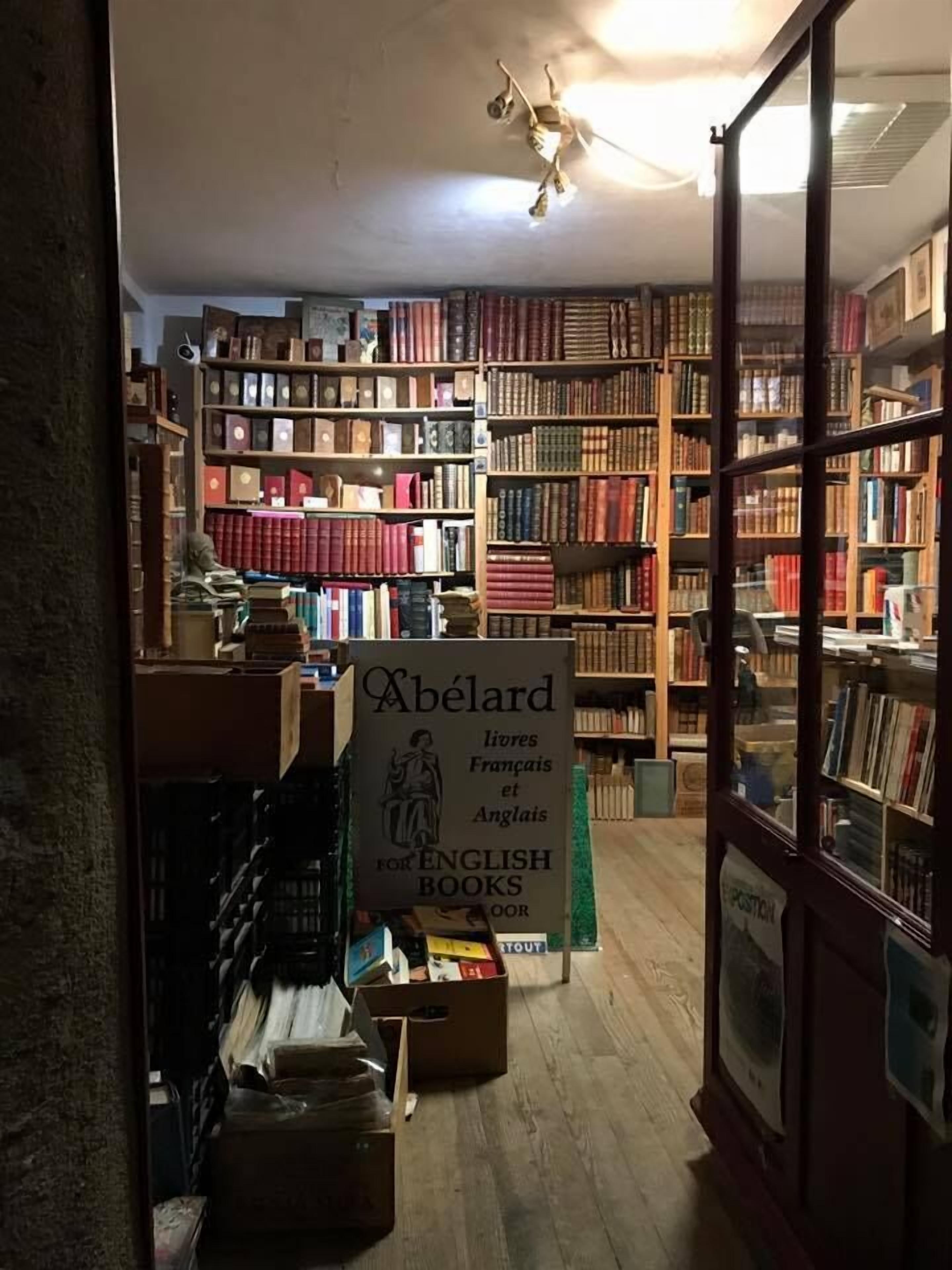 Une librairie avec des étagères en bois remplies de livres. Une enseigne indique qu’elle propose des livres en français et en anglais.