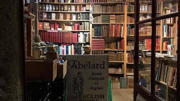 A bookstore with wooden bookshelves filled with books. A sign indicates it offers French and English books.