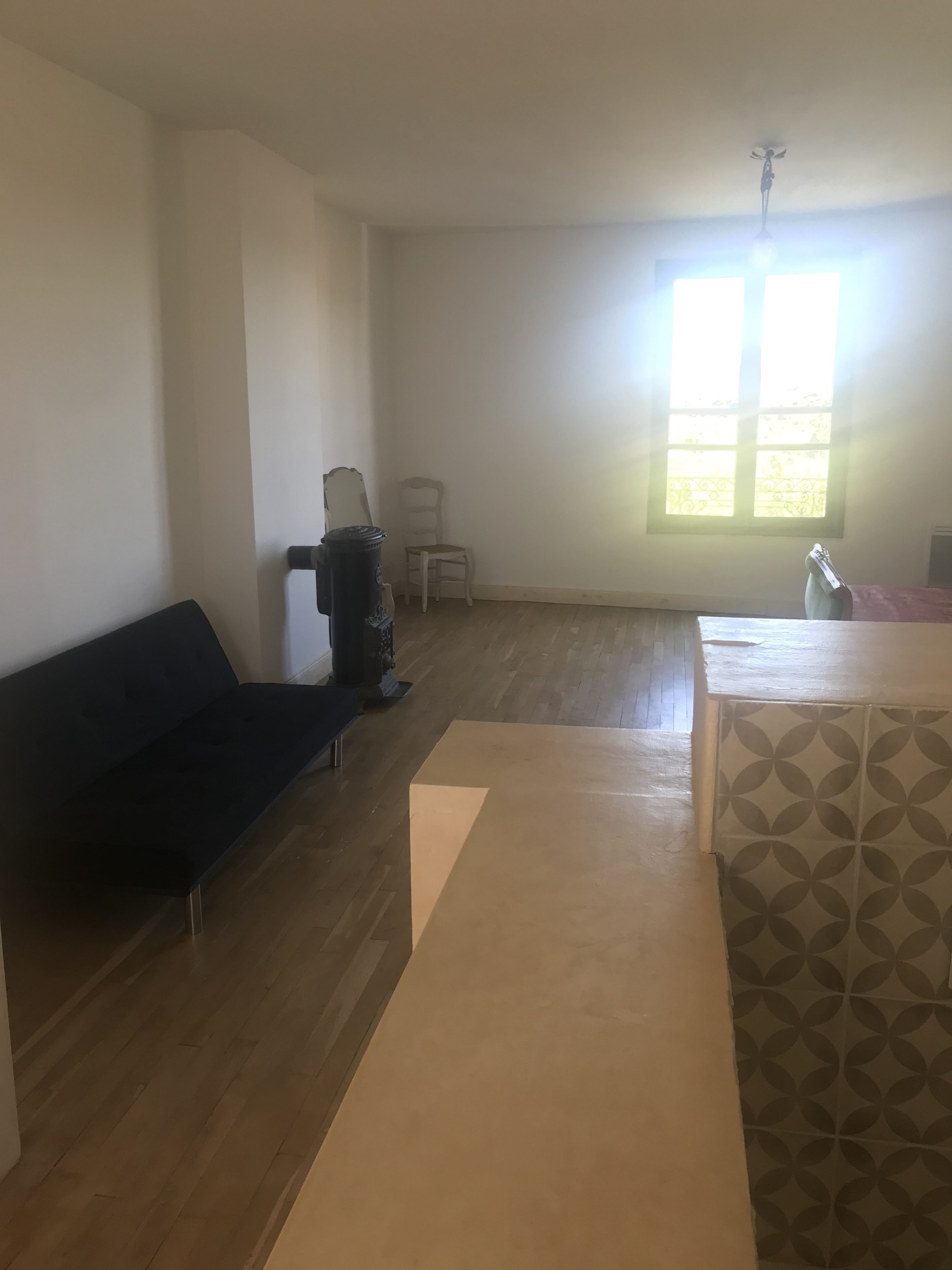 Una habitación con un sofá de color oscuro, una mesita, una silla y un papel tapiz estampado.