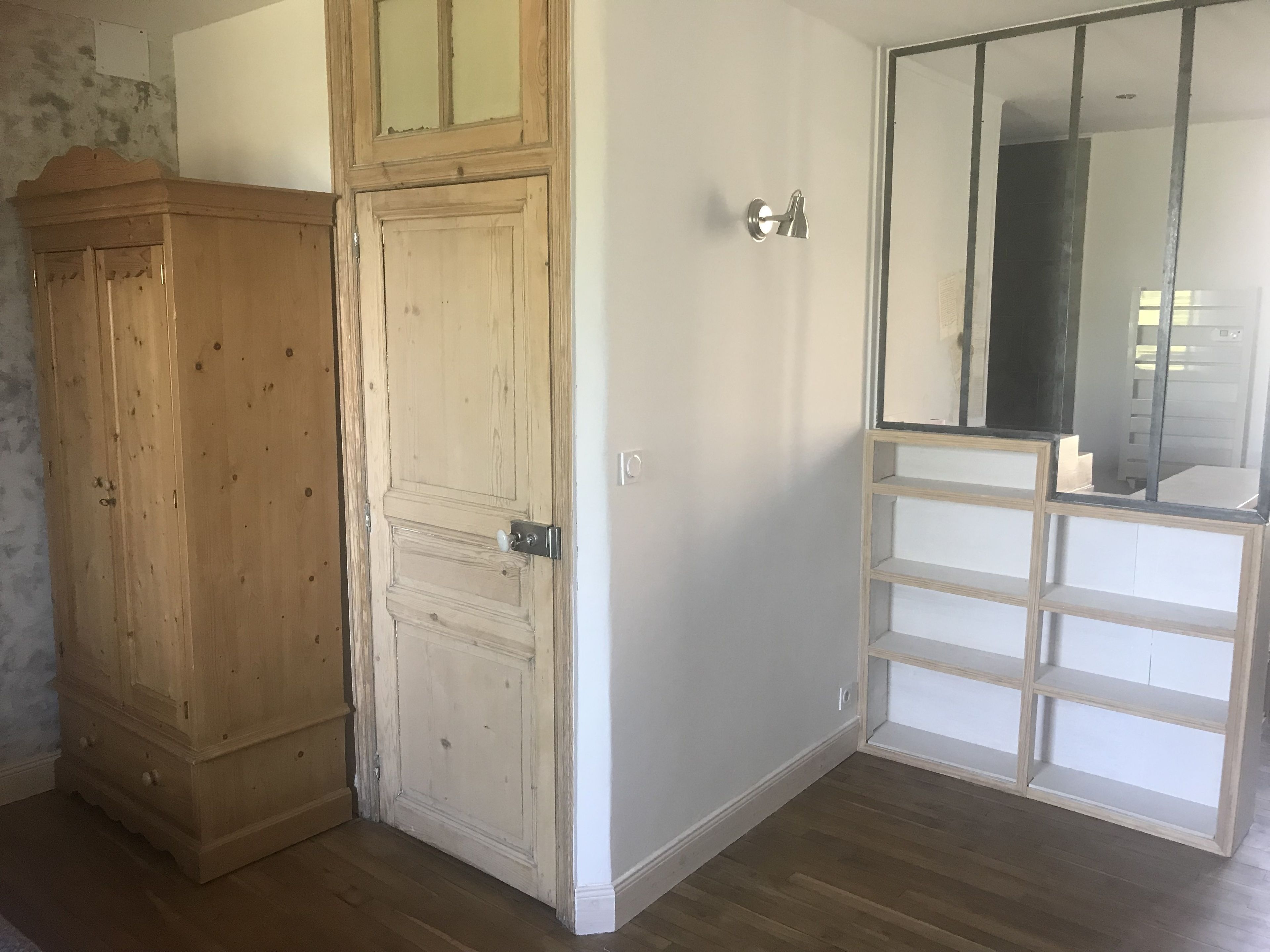 A room with a wooden wardrobe, a white door, and a mirrored closet.
