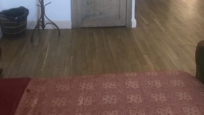 A wooden door with a handle, a coat rack, a trash bin, and a patterned rug. - Librairie Abelard (Montolieu)