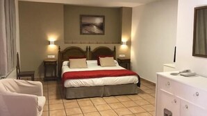 A hotel room with a bed, bedside lamps, a desk, and a cabinet. - Hotel Patri (Huescar)