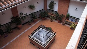 A courtyard with a tiled floor, potted plants, and a decorative metal fence. - Hotel Patri (Huescar)