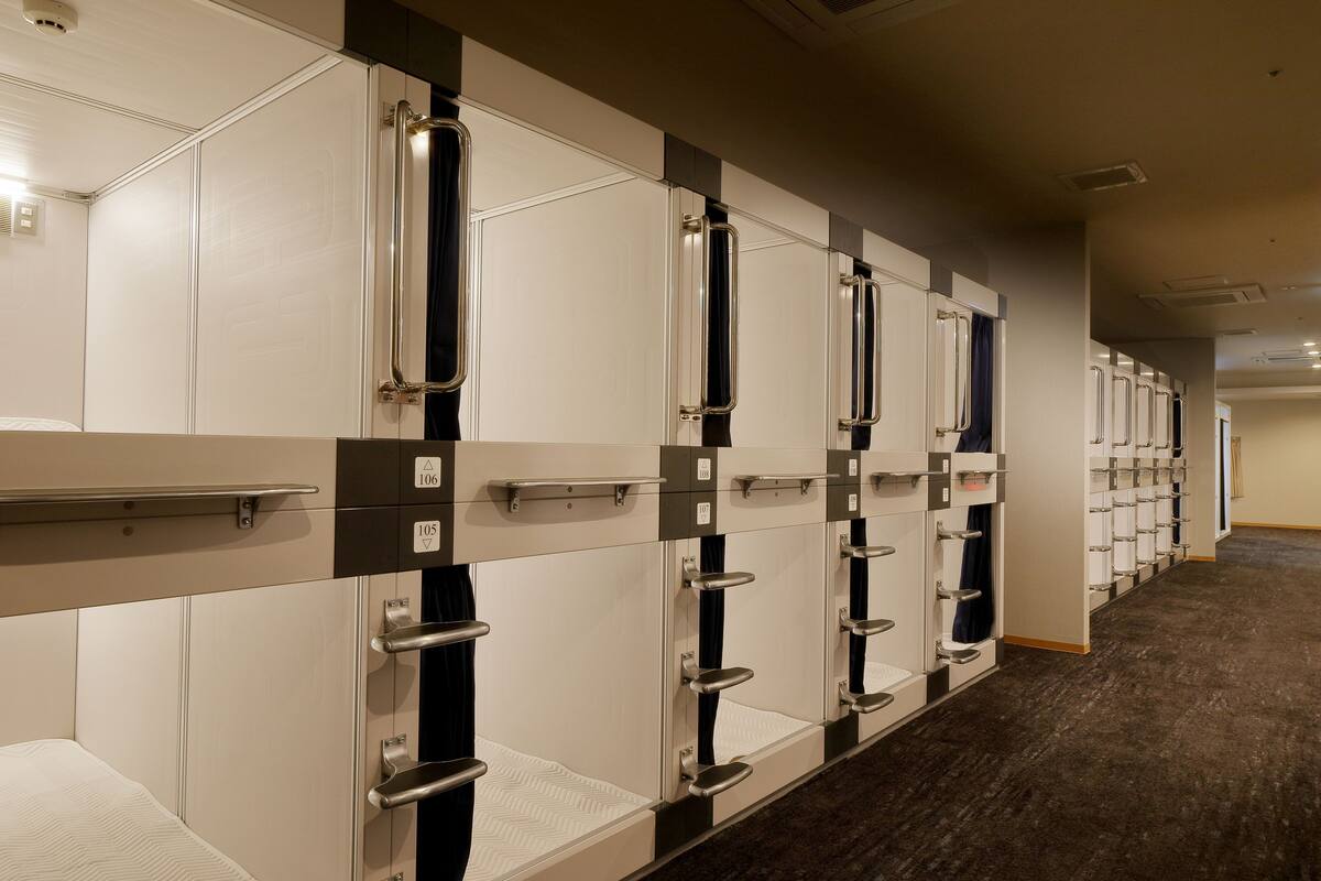 A row of hotel rooms with individual door handles and numbered room signs.