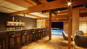A bar area with wooden beams, a bar counter, and several bar stools. - Yurakujo (Tomisato)