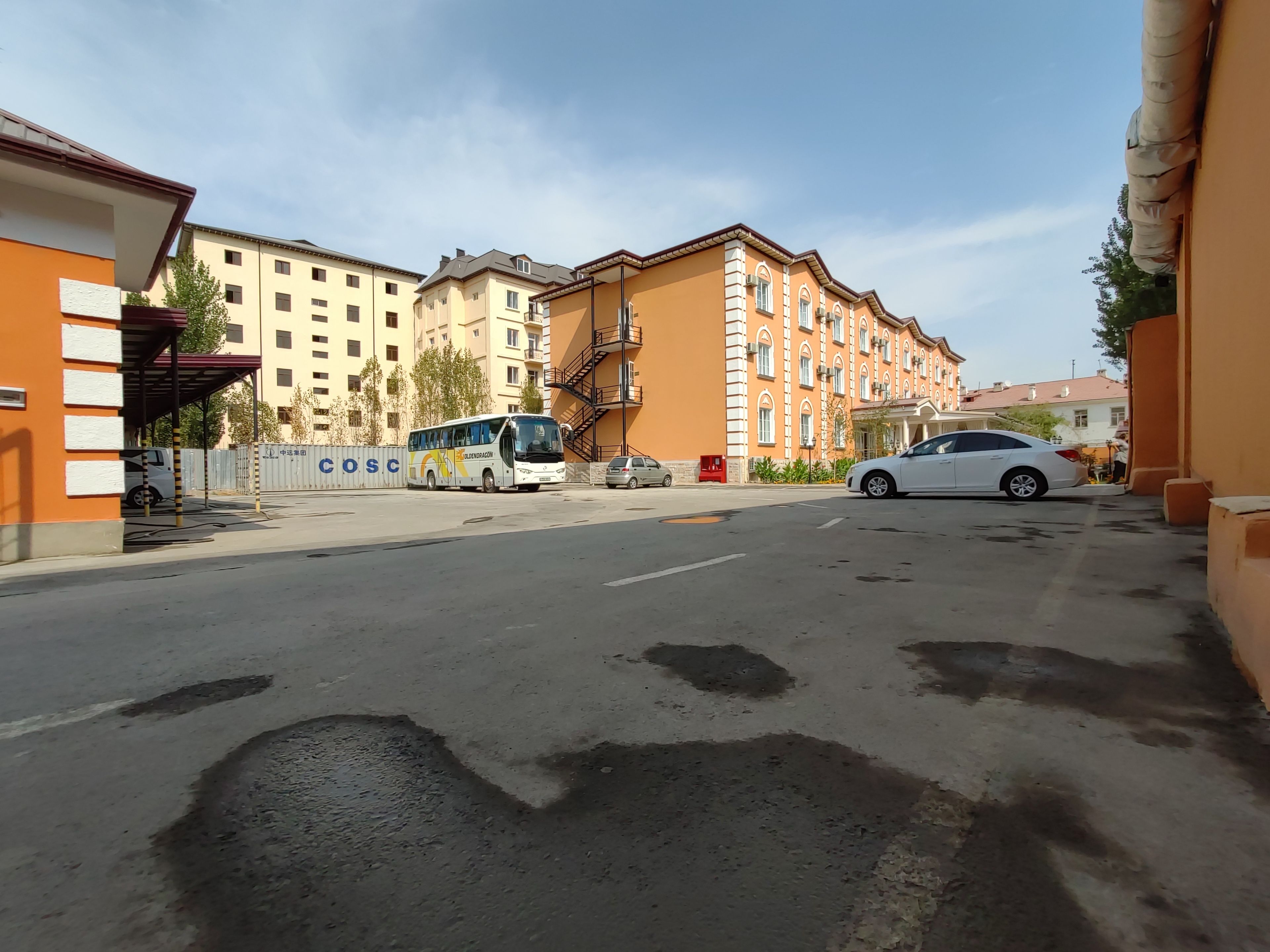 A street with a bus, a white car, and multi-story buildings.