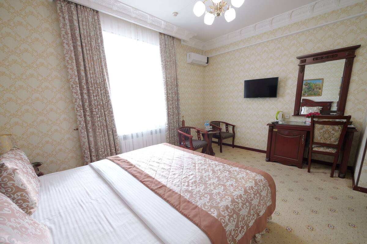 Een hotelkamer met een groot bed, een bureau, een stoel, een televisie en een spiegel.